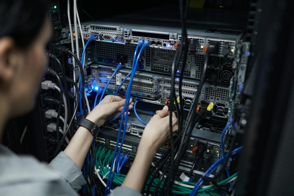 A person connecting cables on a server with visible blue and black wires.