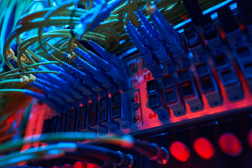 Close-up of colorful network cables connected to a server in a dark environment.